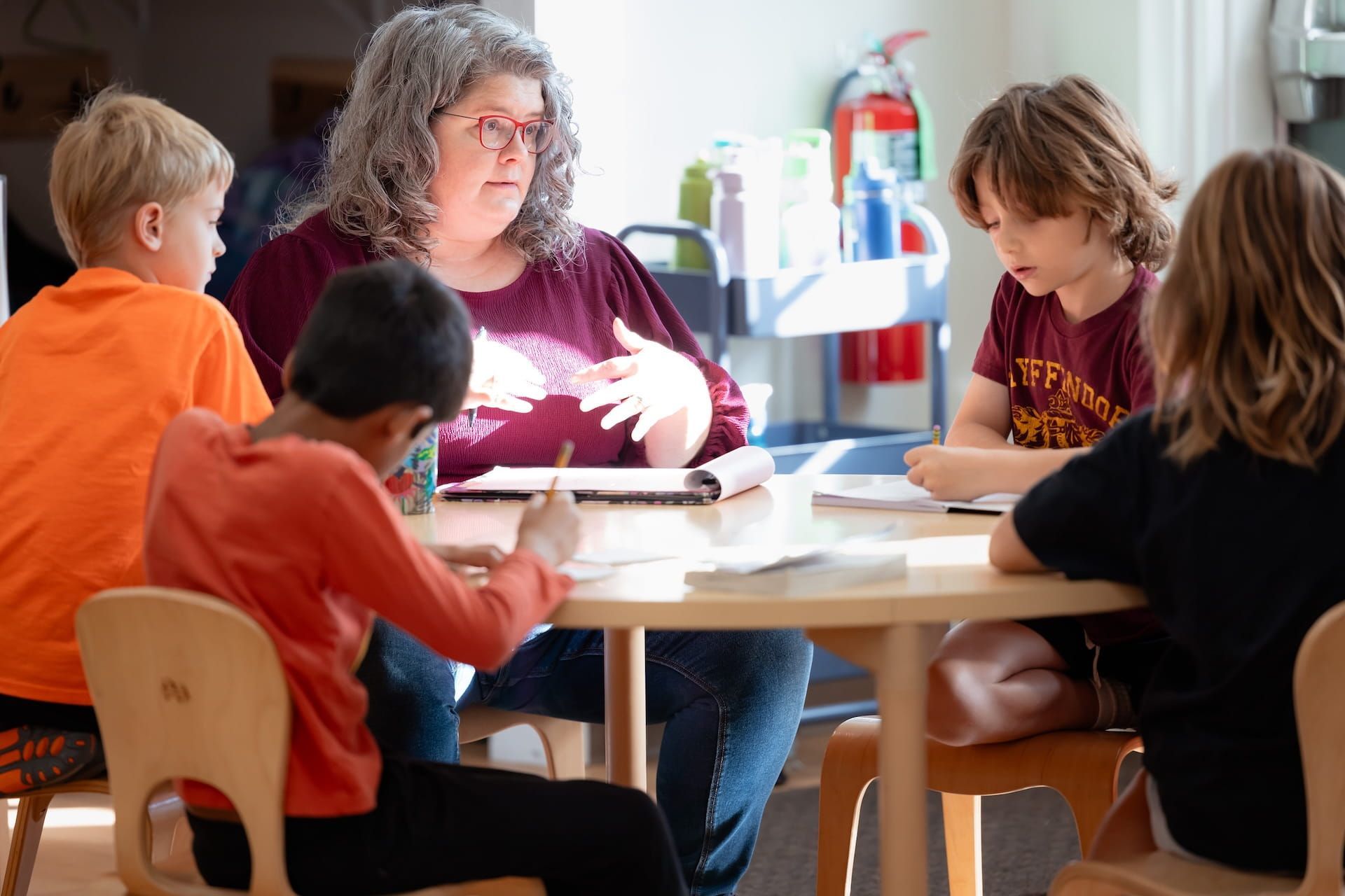 Teacher guiding children working together at table in Montessori classroom
