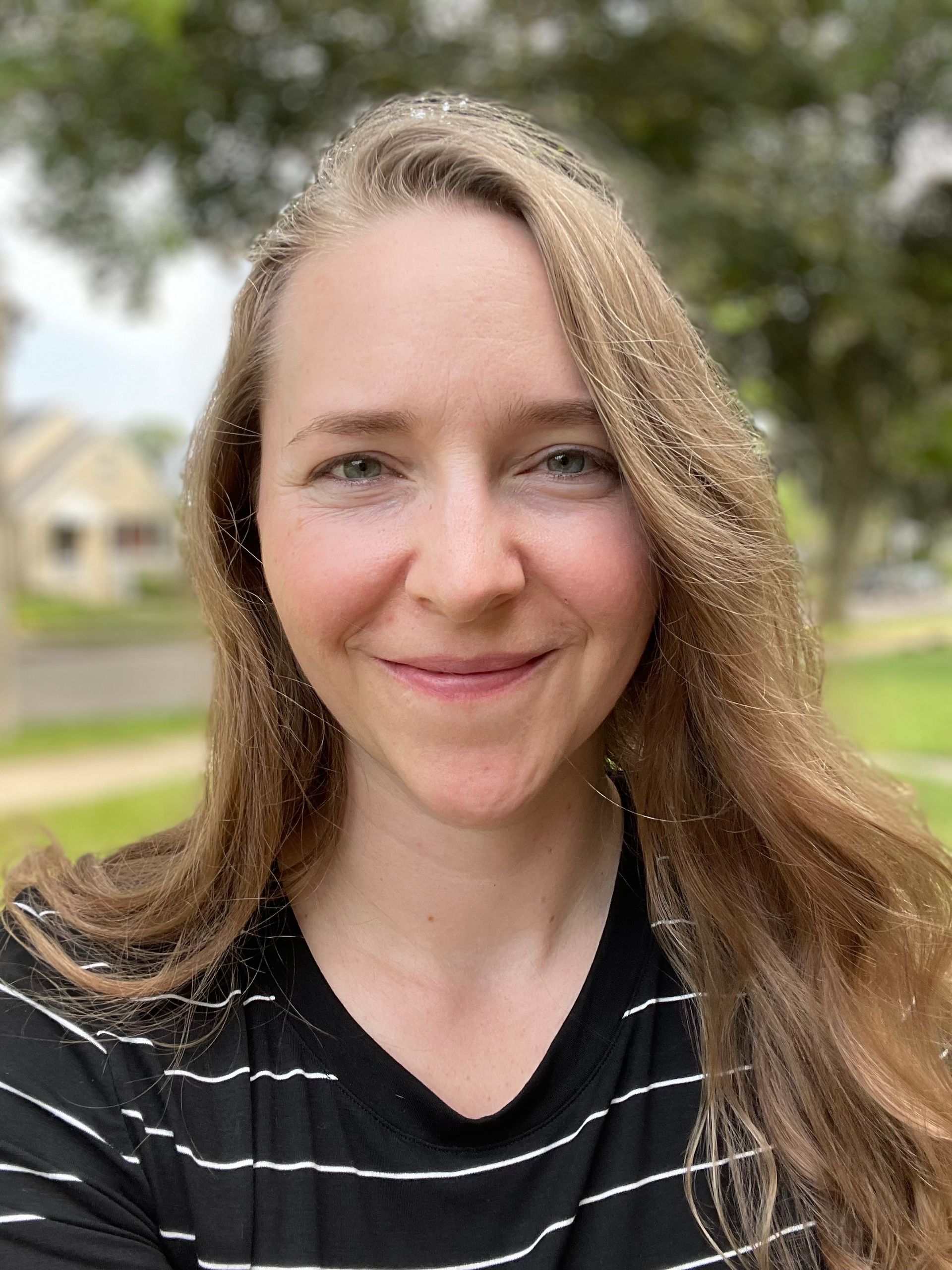 A woman in a black and white striped shirt is smiling for the camera.