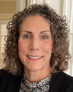 A woman with curly hair is smiling for the camera.