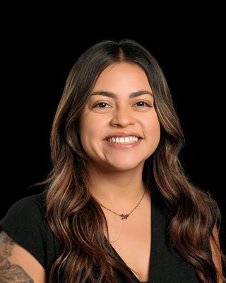 A woman in a red and white polka dot shirt is smiling for the camera.