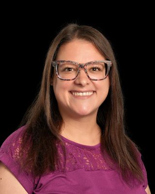 A woman in a red shirt is smiling for the camera.