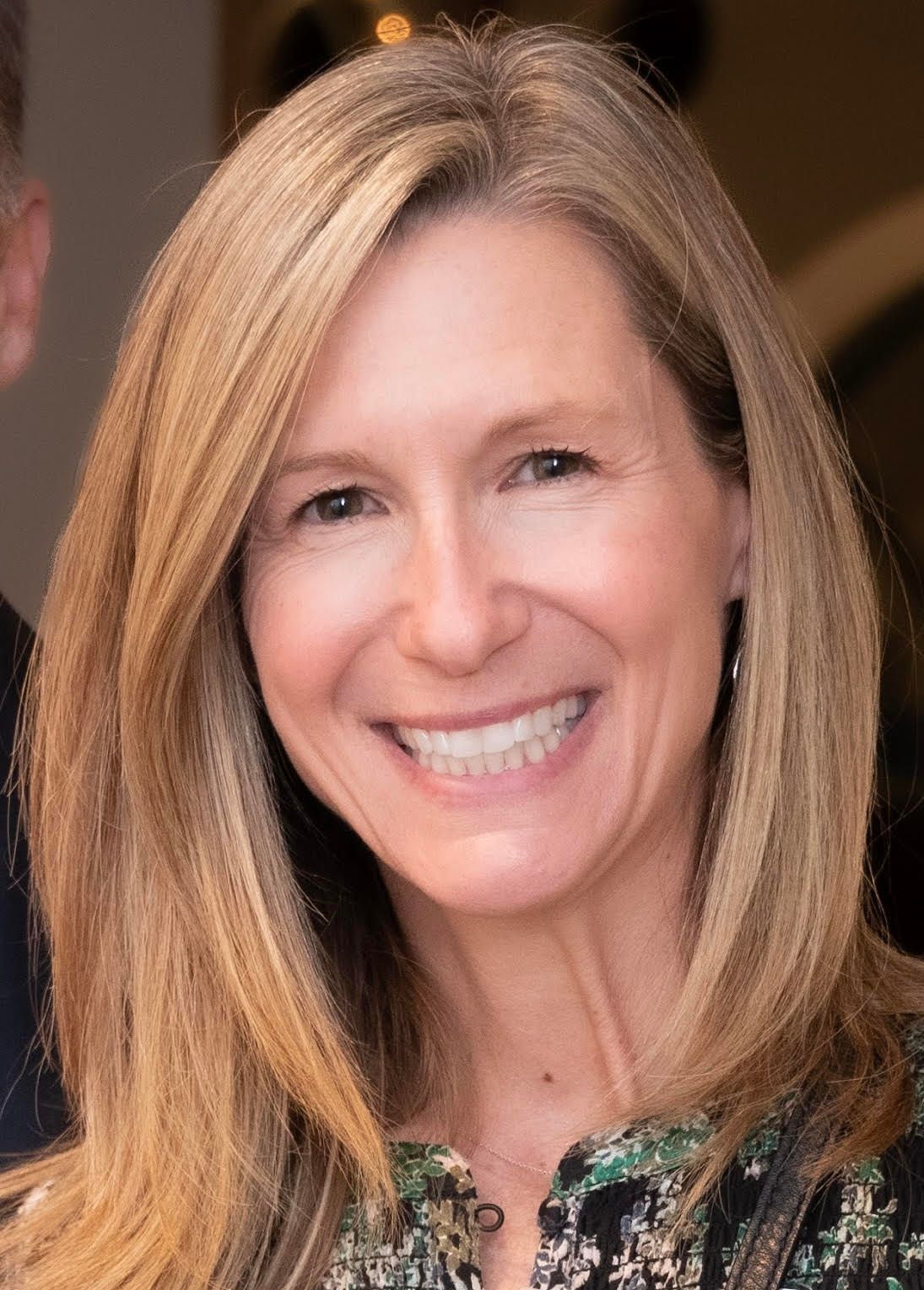 A woman with long blonde hair is smiling for the camera.