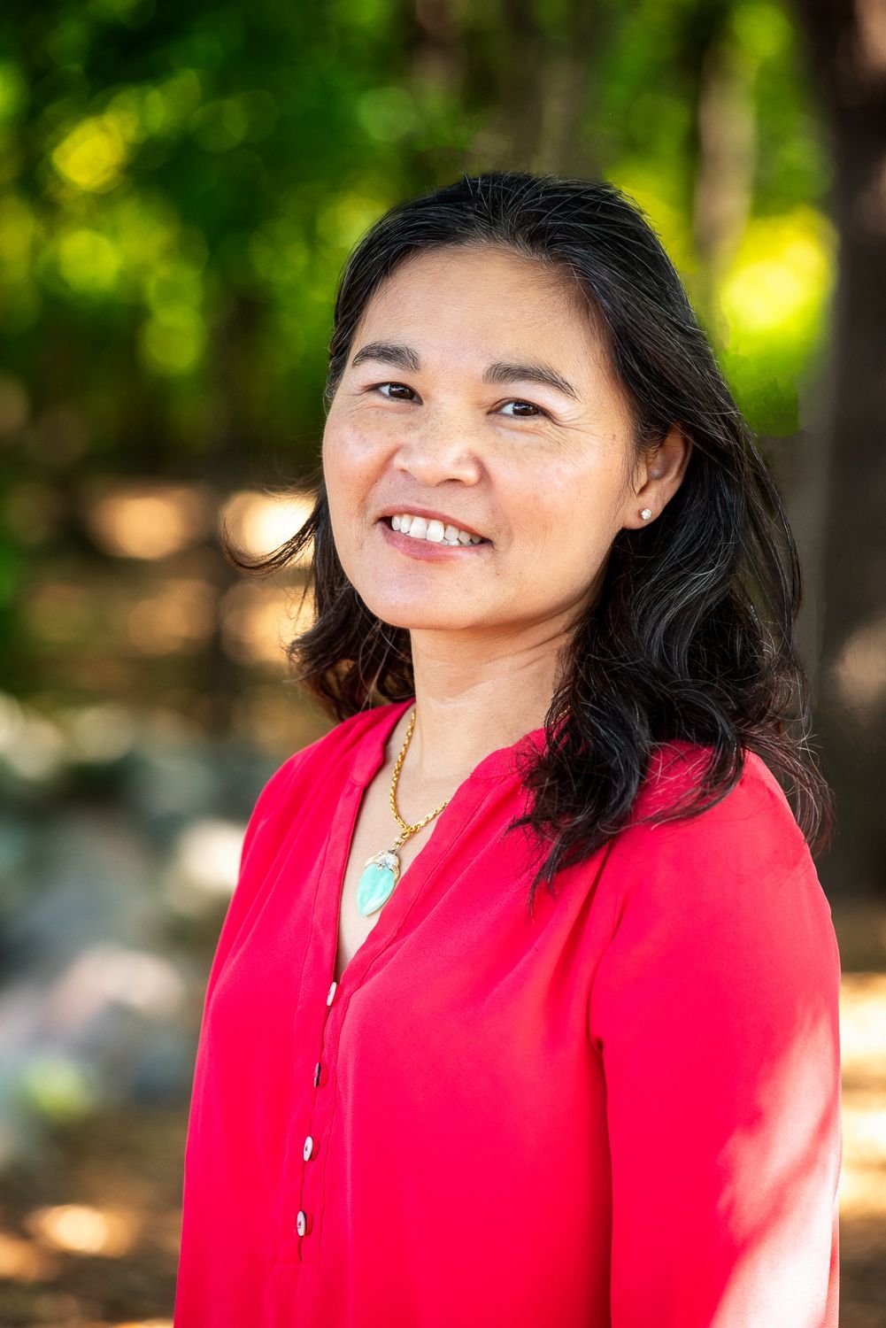 A woman in a red shirt is smiling for the camera.