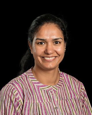 A woman in a blue shirt and green lanyard is smiling for the camera.