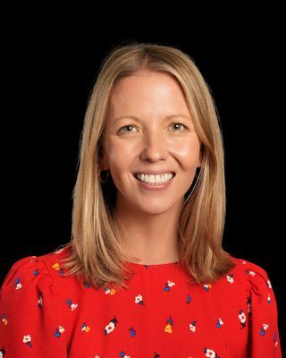 A woman in a denim jacket is smiling for the camera.