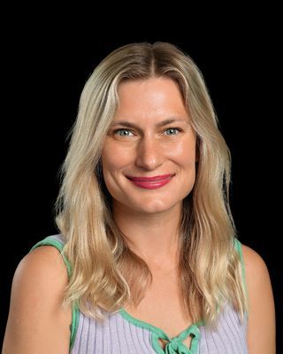 A woman wearing a pink sweater and hoop earrings is smiling for the camera.