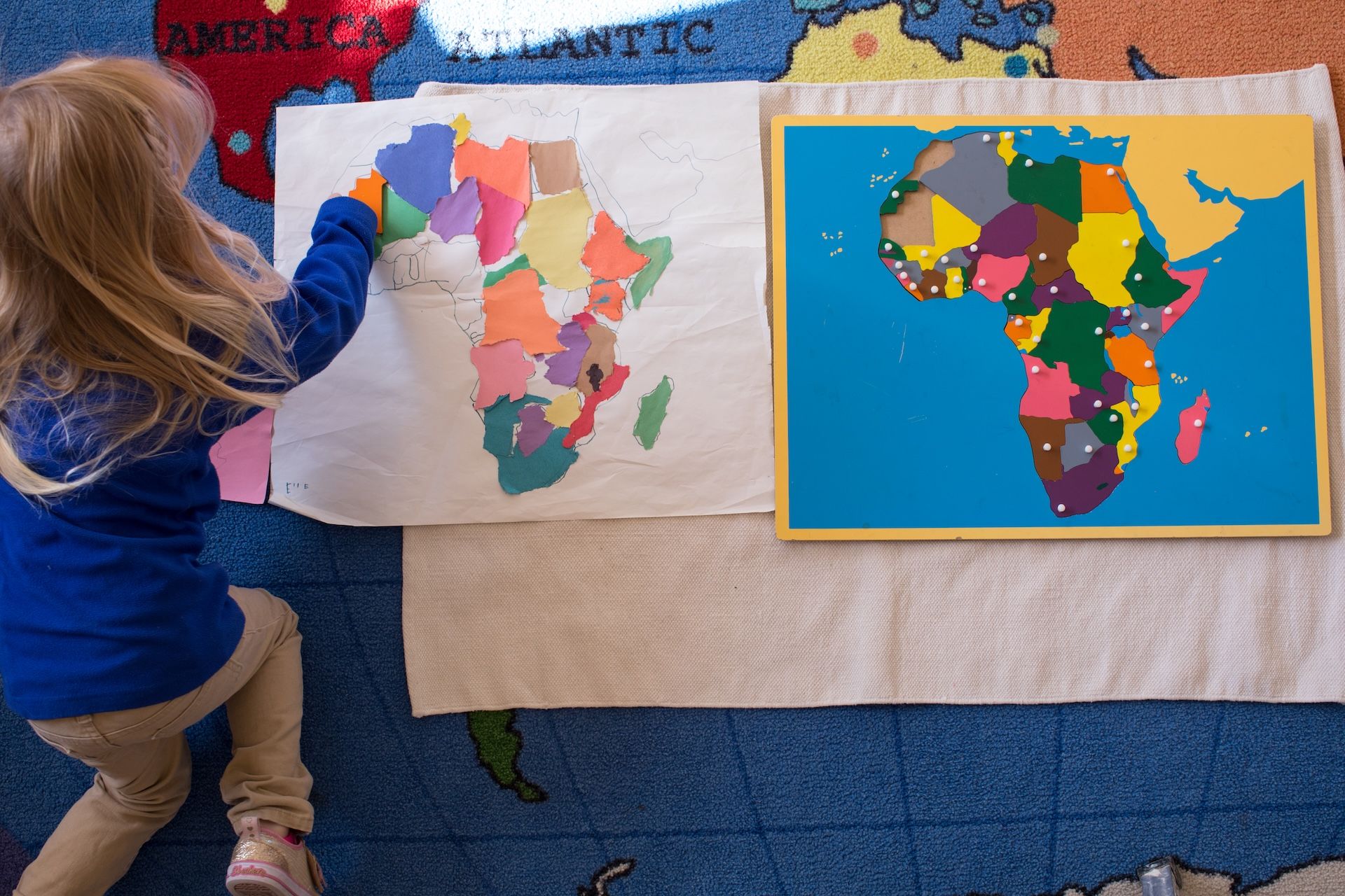 Child placing colorful map pieces on Africa classroom board display