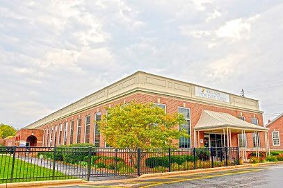 A large brick building with a fence around it and a porch.