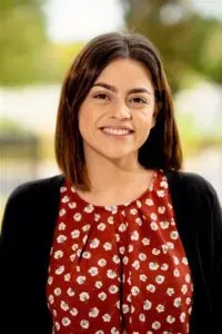 A woman in a red and white polka dot shirt is smiling for the camera.