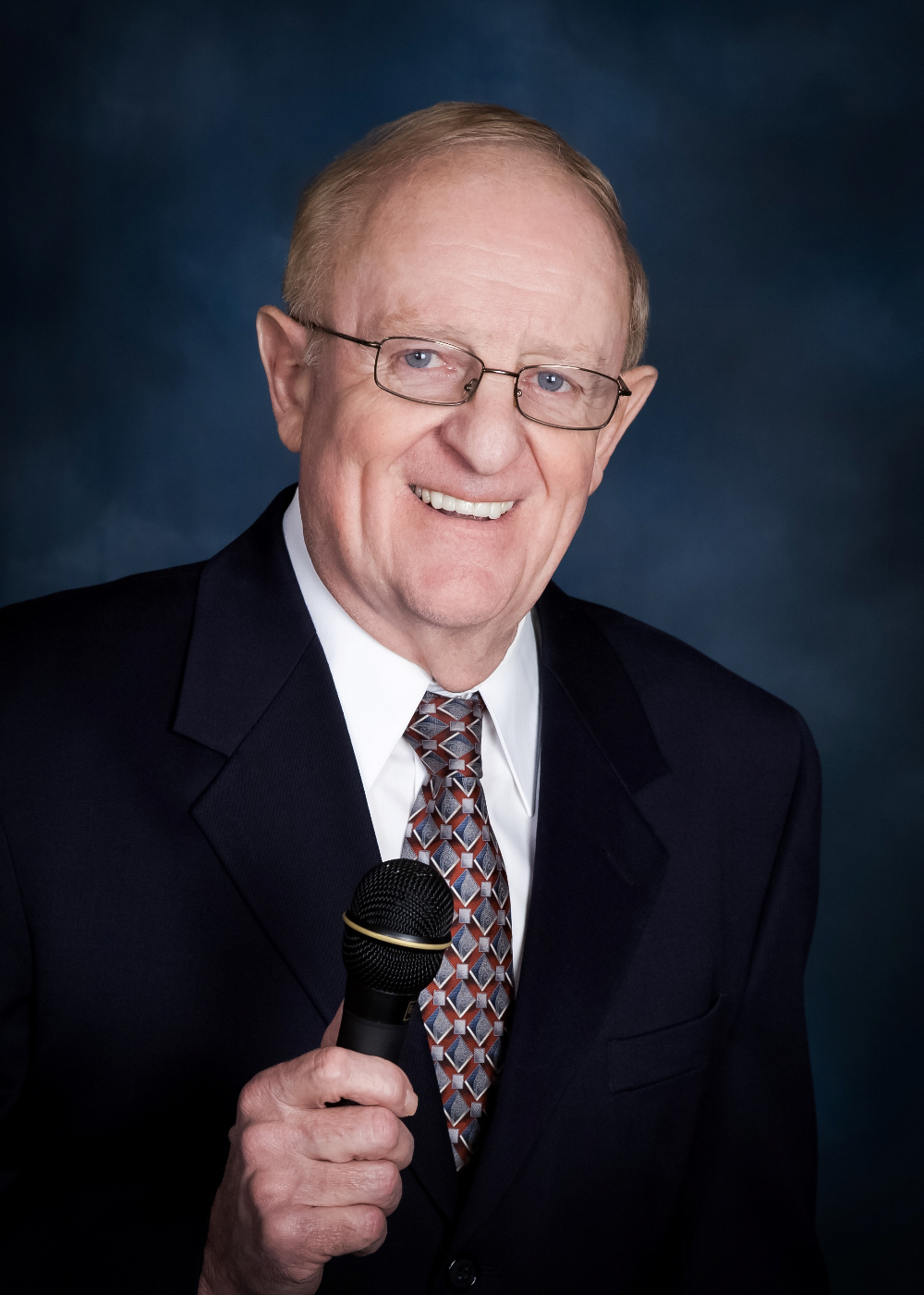 A man in a suit and tie is holding a microphone