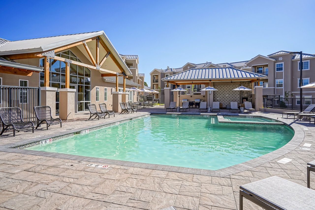 Outdoor pool area at an apartment community with lounge chairs and shaded seating.