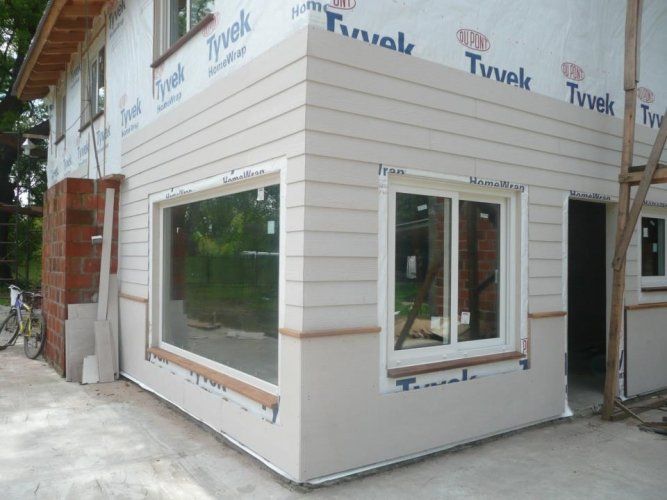 Un rincón de una casa con una ventana y revestimiento de tyvek.