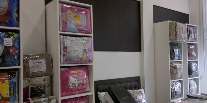 Un dormitorio con una cama y estantes llenos de mantas y almohadas.