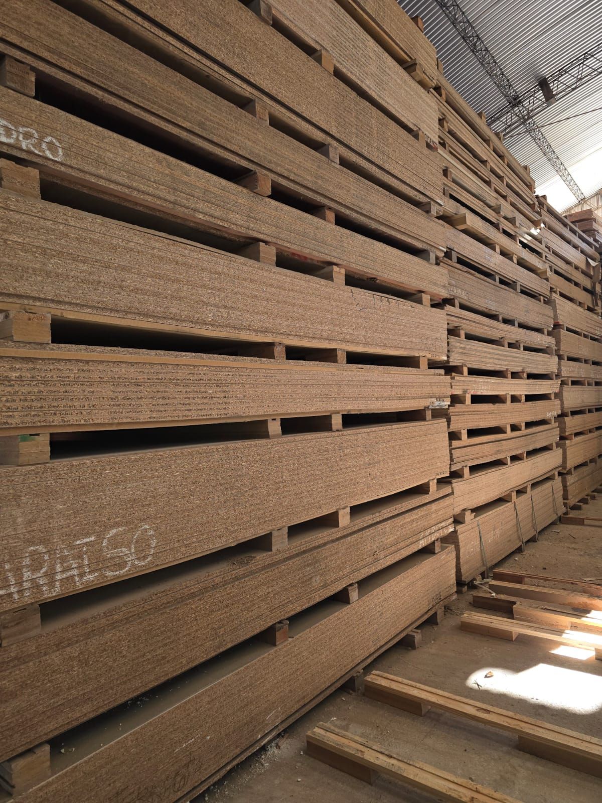 Un almacén lleno de montones de paletas de madera apiladas una encima de otra.