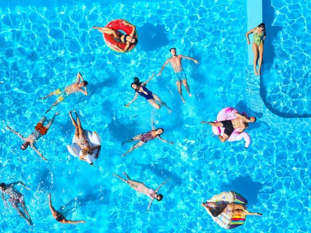People floating in a bright blue swimming pool on a sunny day.