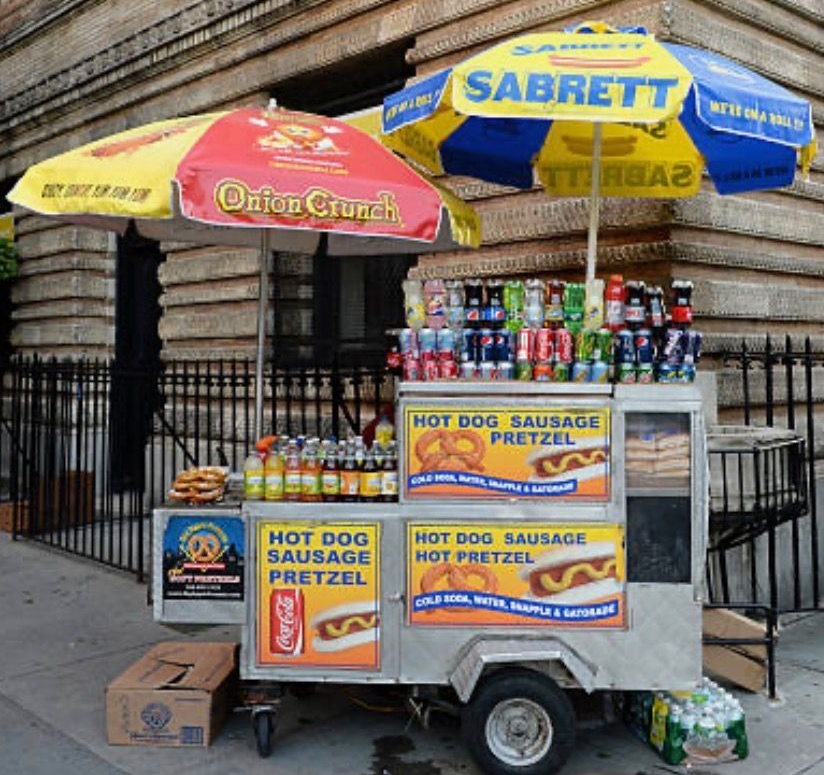Couple receiving food from a food truck vendor. Outdoor setting; food truck with lights and decorations.