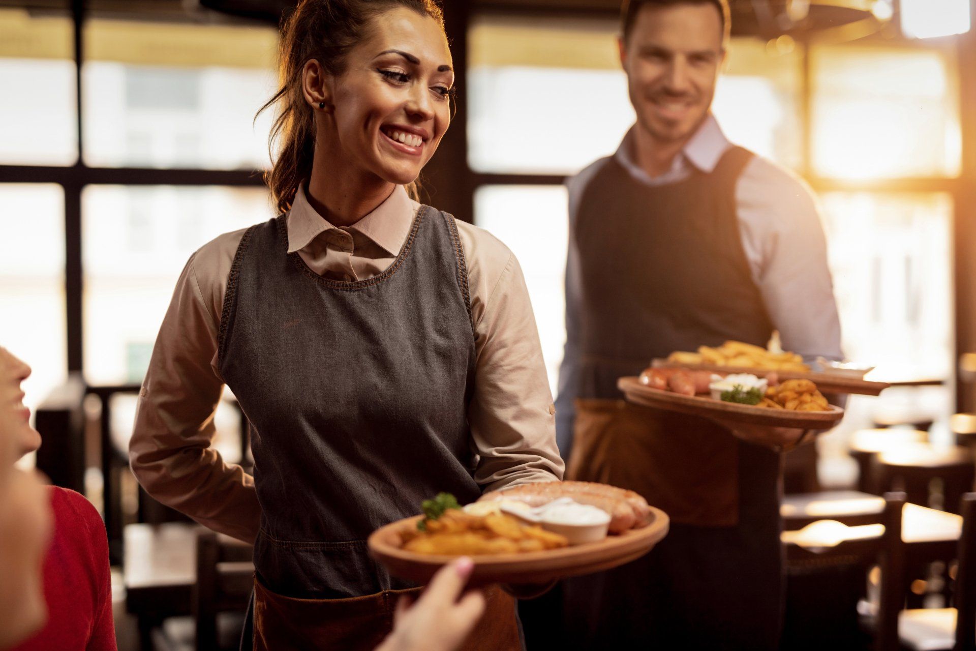 Two waiters serving lunch and brining food to their gusts in a tavern.
