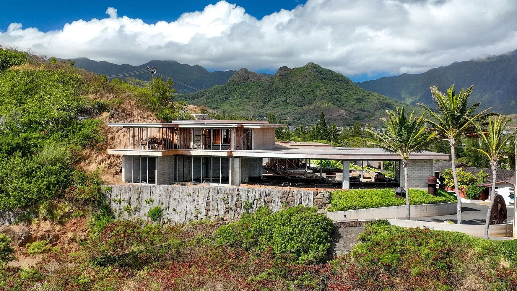 Modern house built into a hillside with mountain and ocean view.