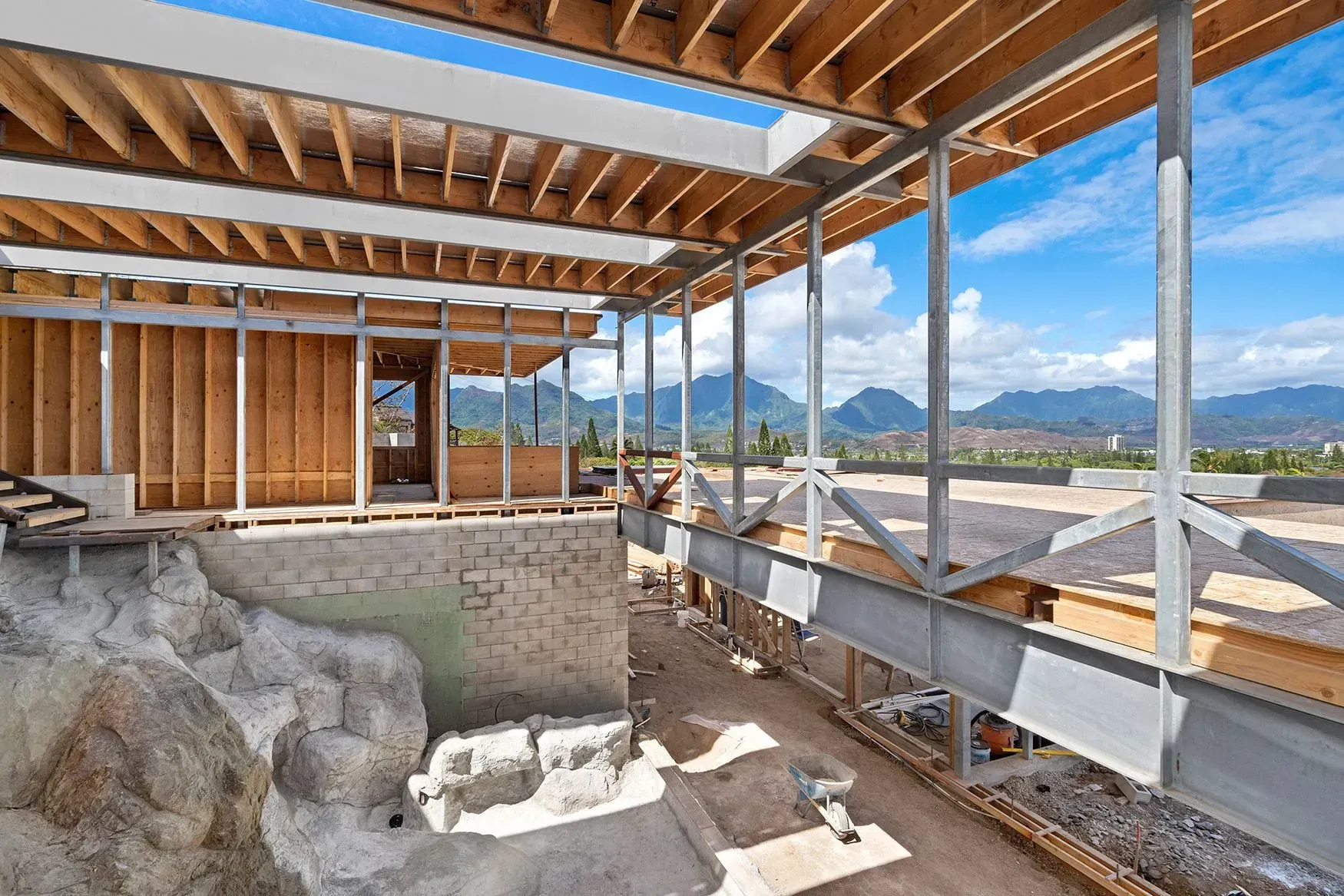 Construction site with wooden beams, steel supports, and scenic mountain backdrop.