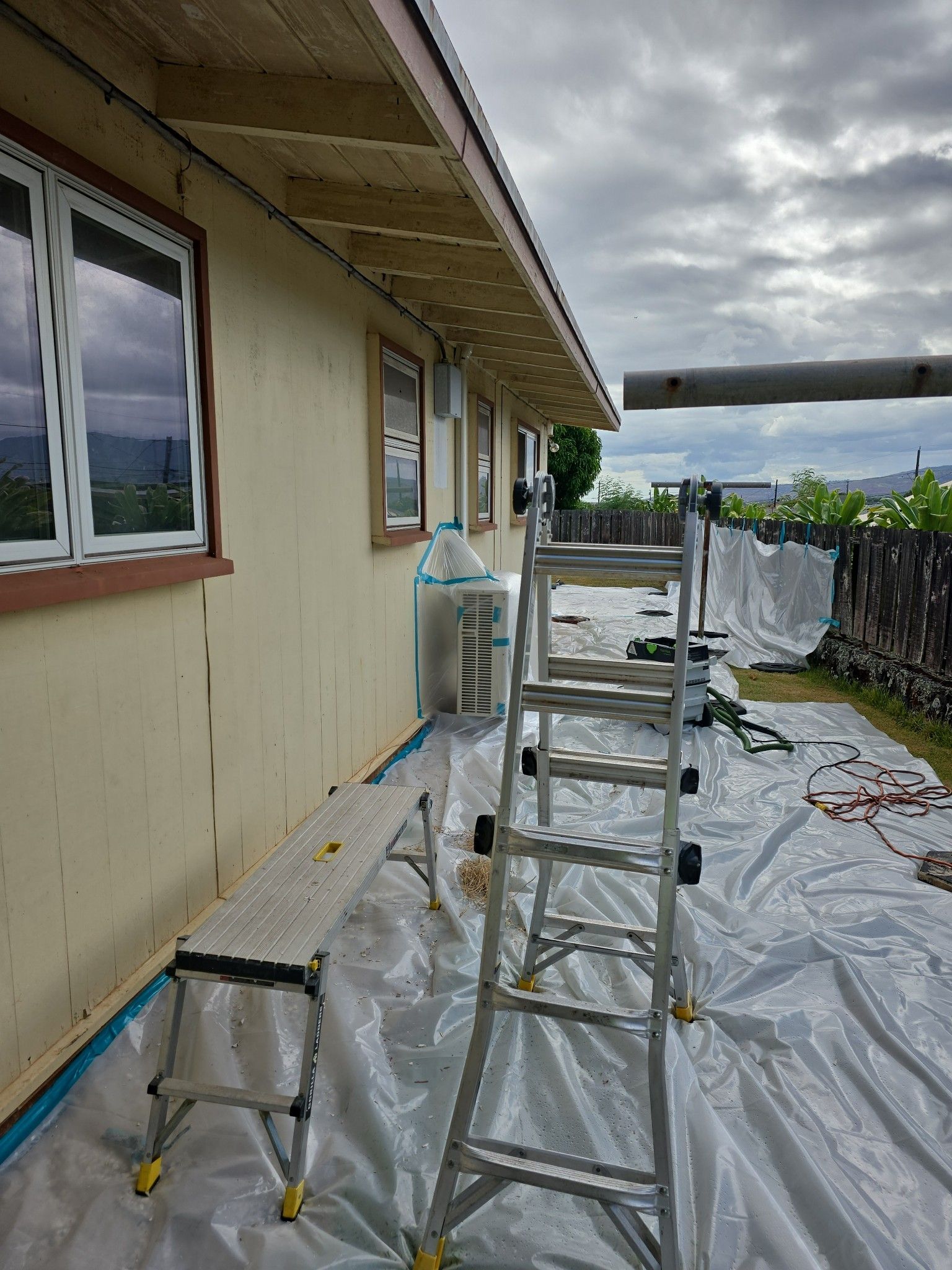 Yellow tape blocks an entryway to a weathered, single-story building; grass and a cloudy sky are visible.