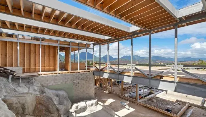 Construction site with exposed wooden beams, framing, and a mountain view.