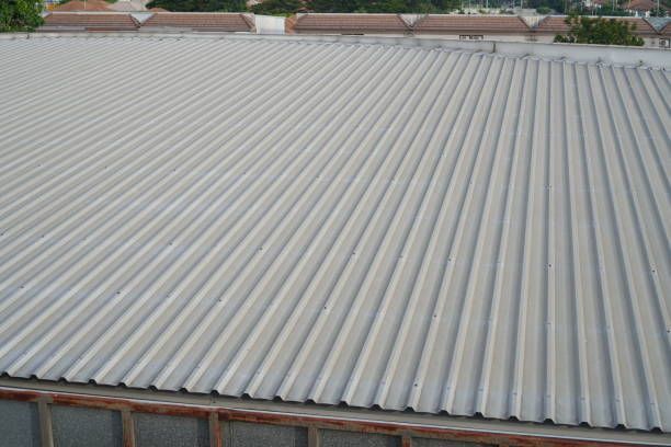 Top view of a corrugated metal roof on a building with houses visible in the background.