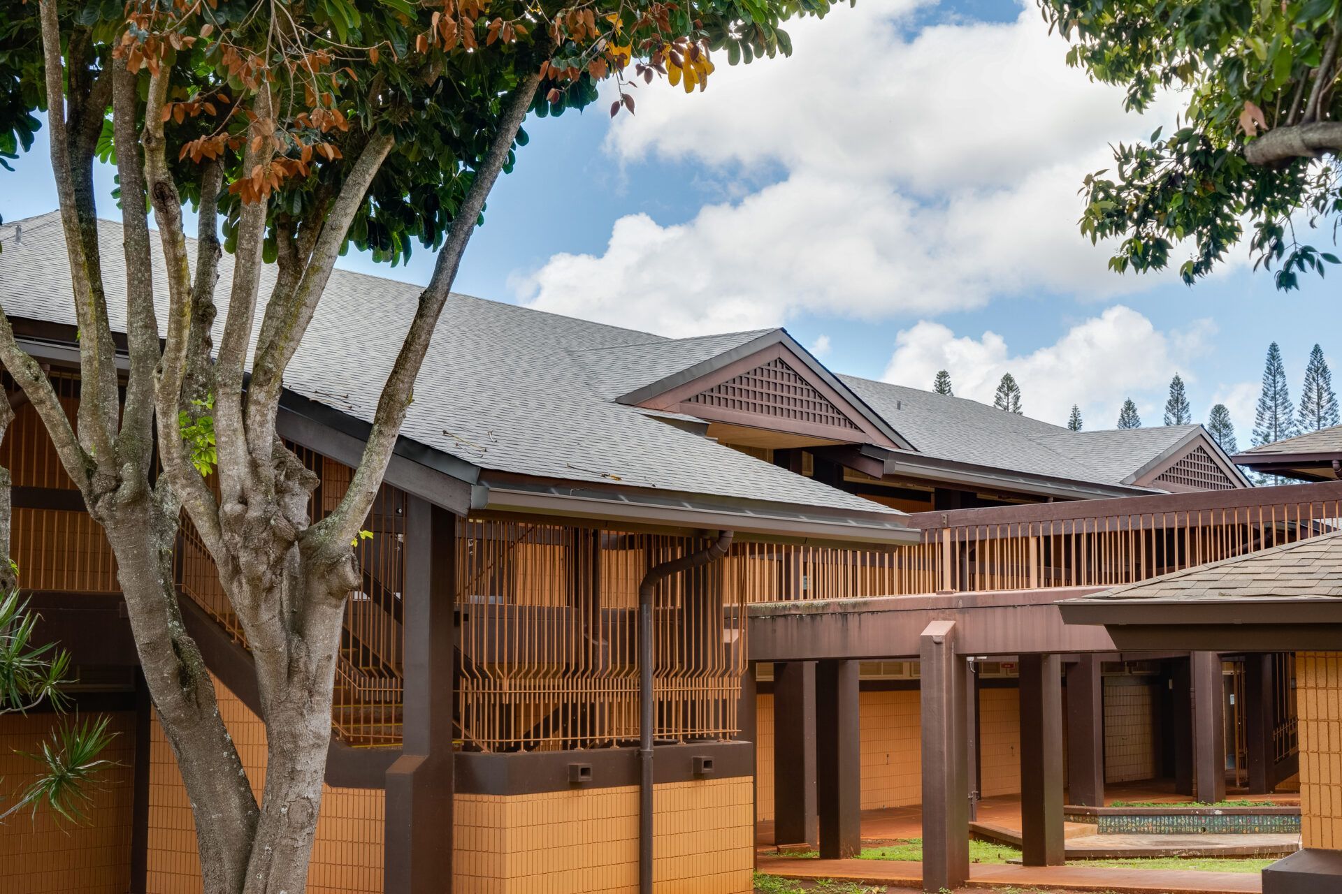 Buildings with brown siding and dark gray roofs, under a partly cloudy sky.