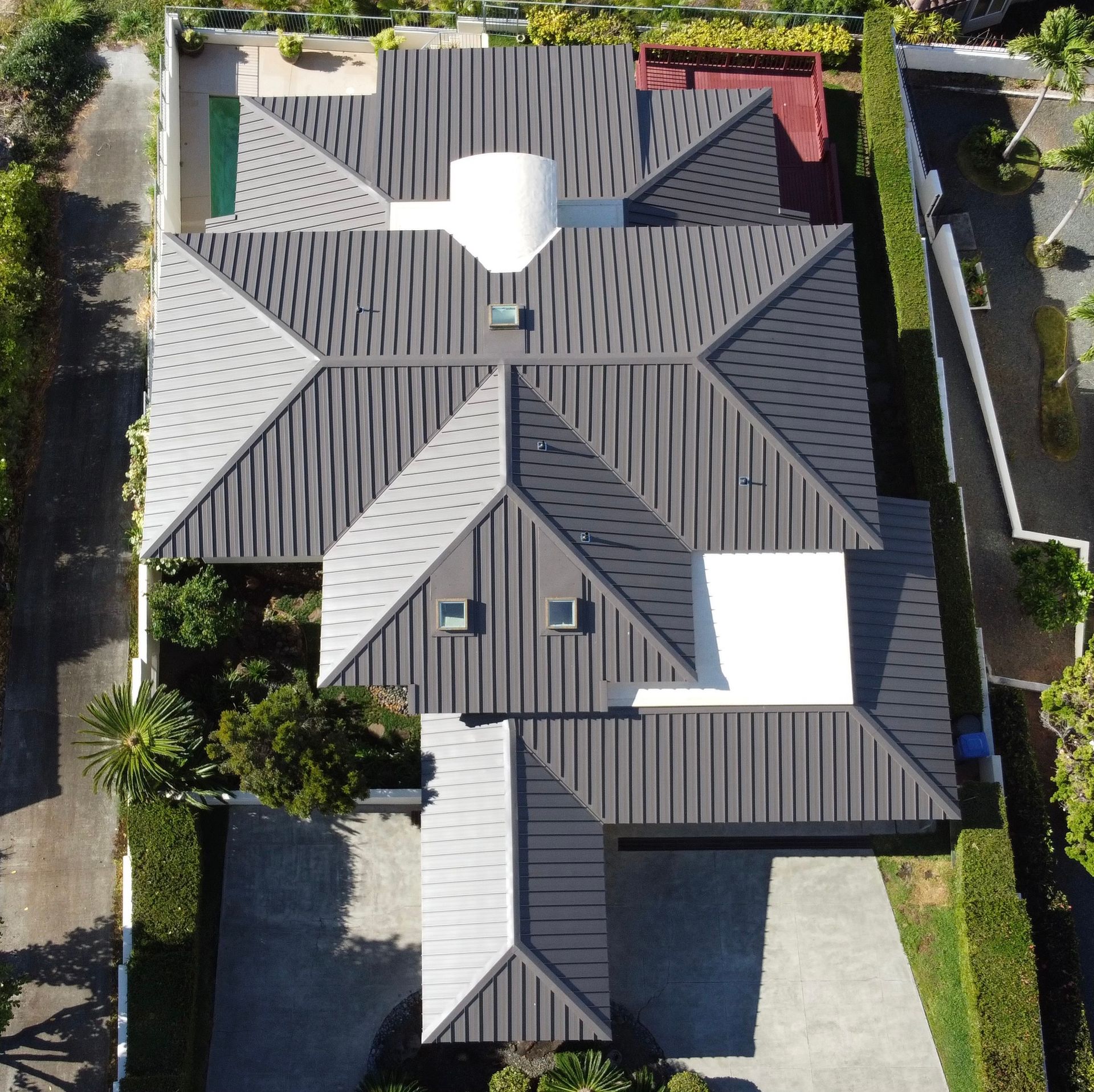 Overhead view of a house with a complex, dark gray roof. Driveway and landscaping.