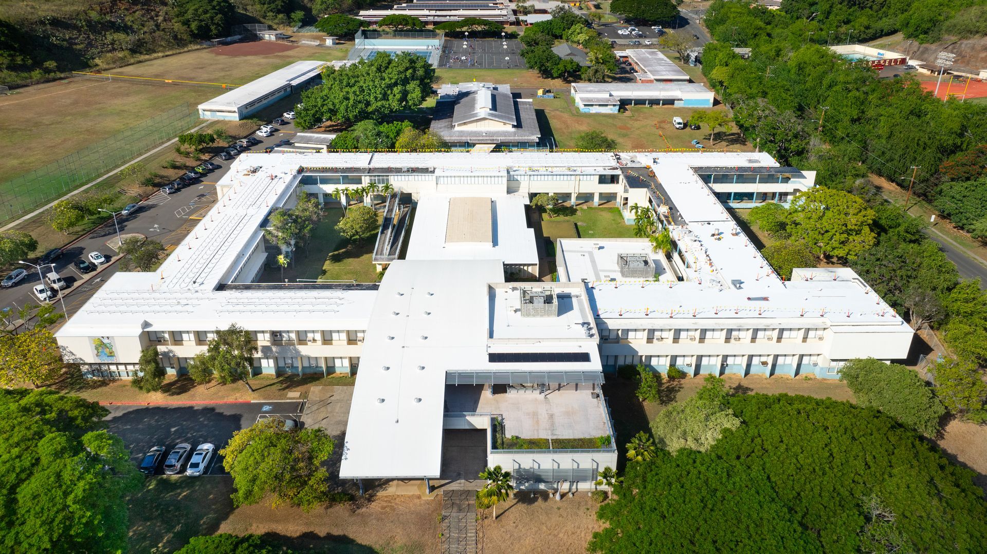 Aerial view of a white, multi-building structure with a central courtyard surrounded by greenery.