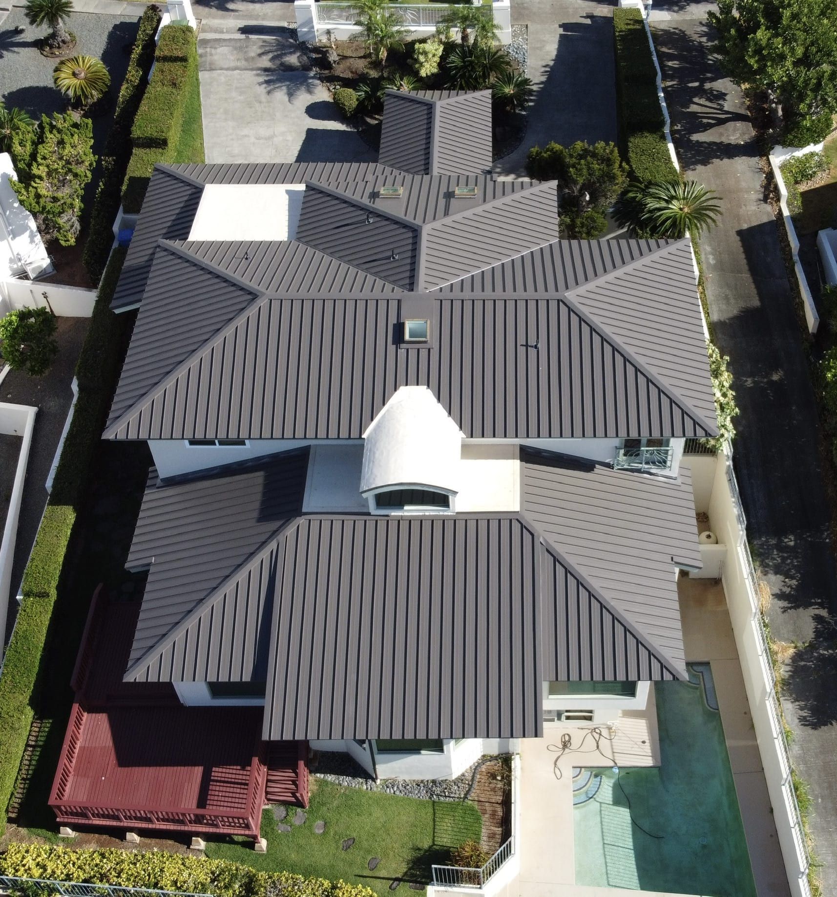 Overhead view of a modern house with a gray roof, white exterior, and a pool.