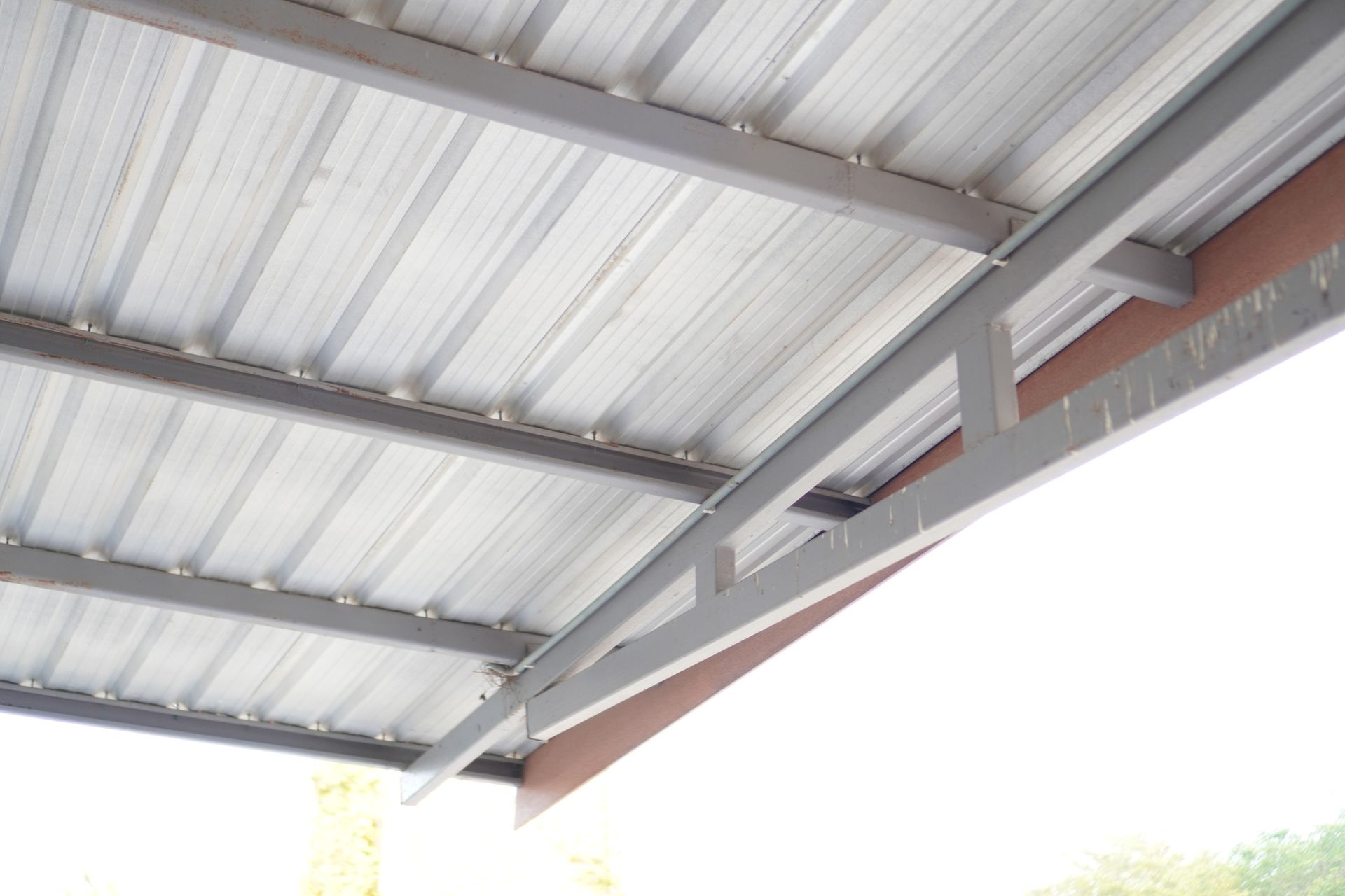 Close-up view of a metal roof with steel beams and panels in bright daylight.
