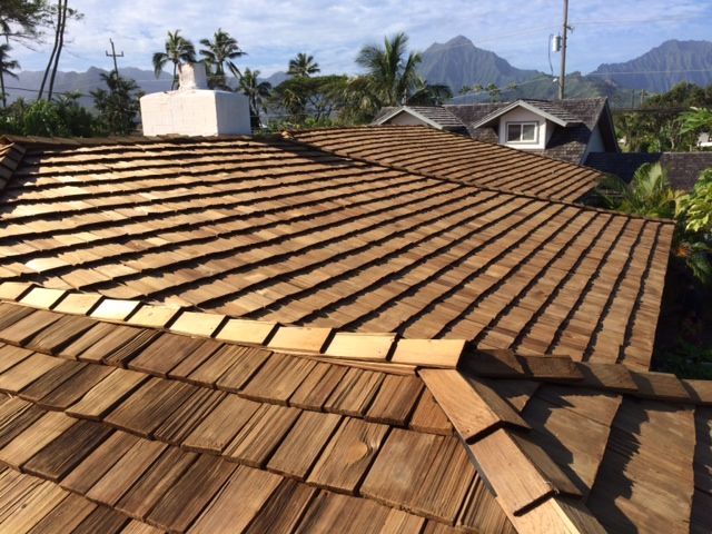 Wooden shingle roof on a house, view overlooking trees and mountains on a sunny day.