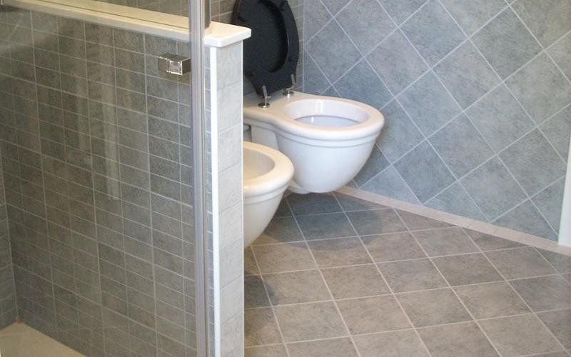 Bagno con piastrelle grigie, doccia, WC e bidet.