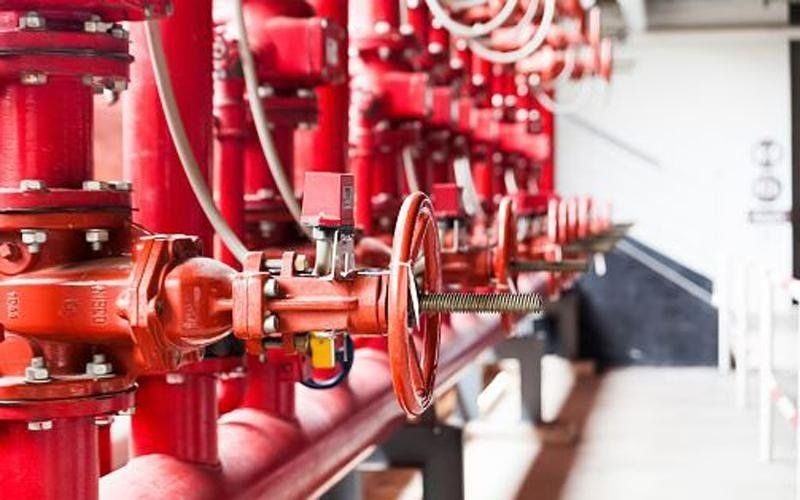 Tubi e valvole rossi del sistema antincendio in un ambiente industriale.