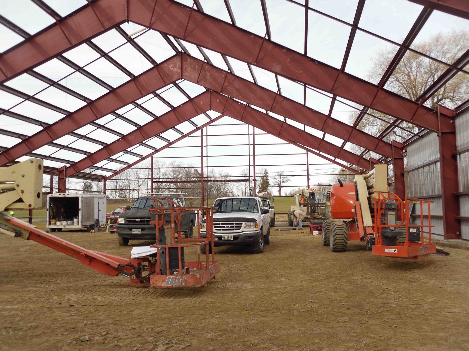 A group of trucks are parked inside of a building under construction.