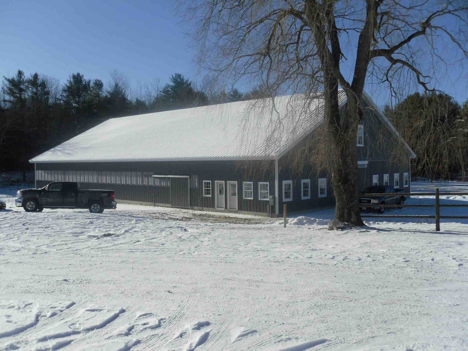 A truck is parked in front of a barn with snow on the ground