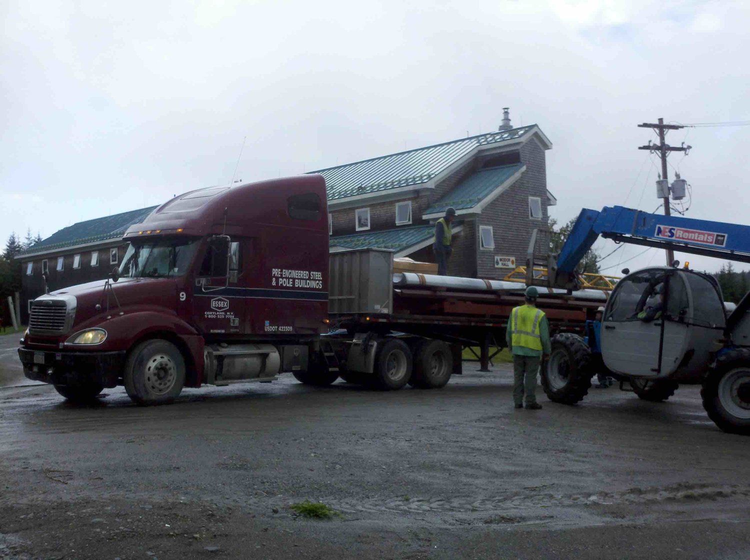 A red semi truck with a crane attached to it