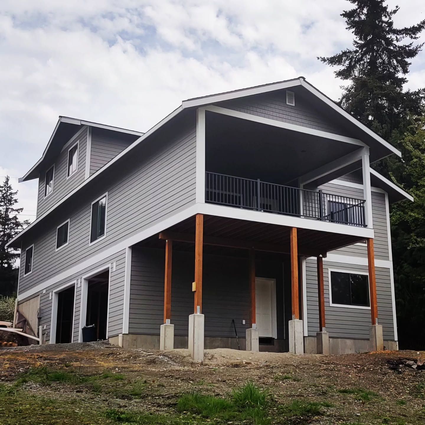 Gray two-story house under construction with a large second-story deck and garage.