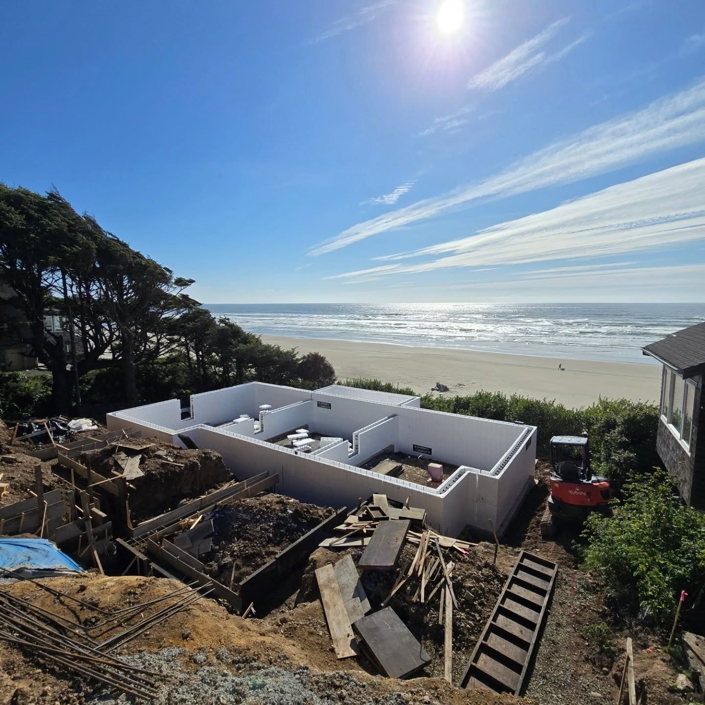 Construction site with white foundation, beach, blue sky.