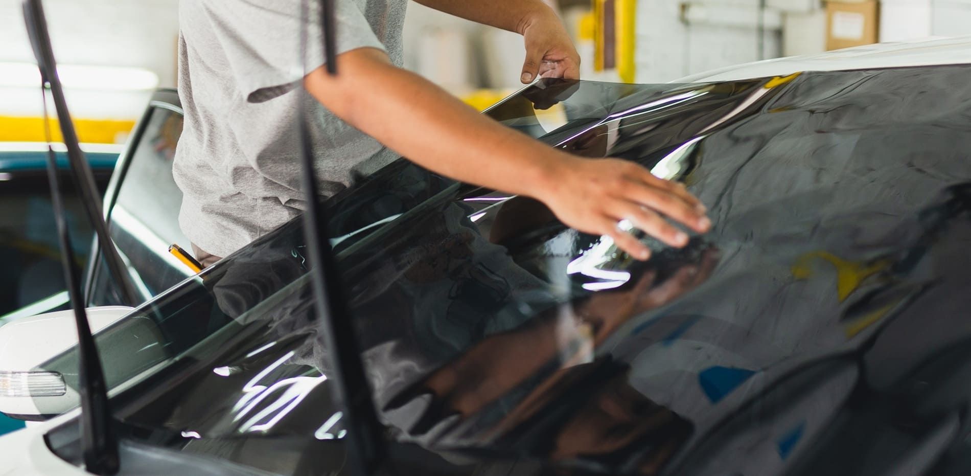 Professional installing windshield tint on a car in Florida