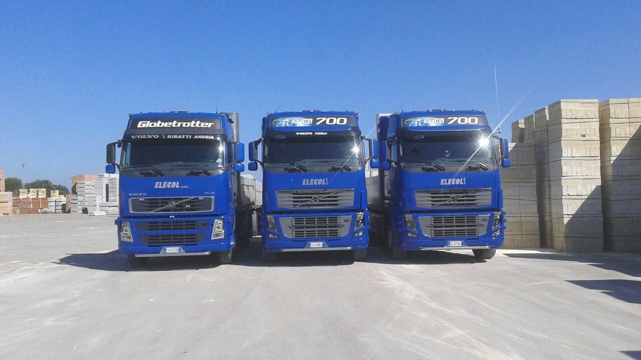 Tre camion blu sono parcheggiati uno accanto all'altro in un parcheggio.