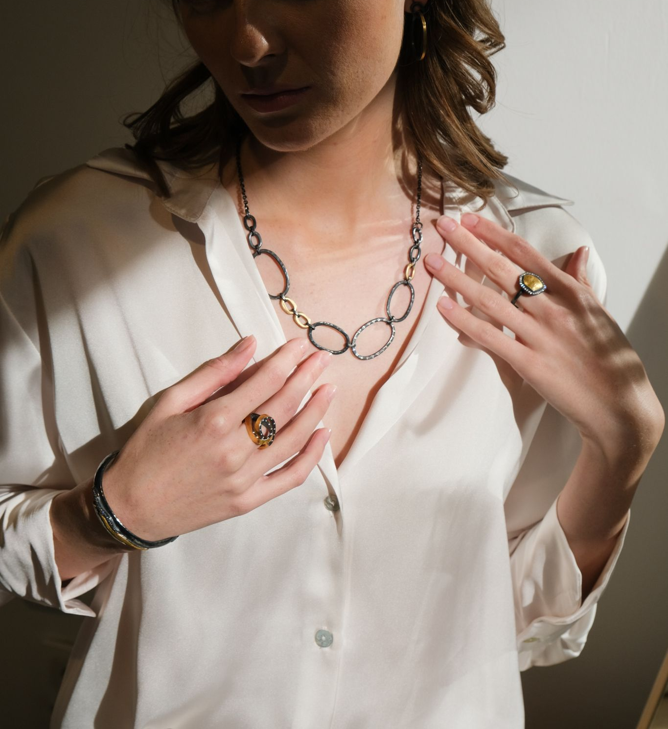 Woman wearing jewelry, wrapped in white fabric, looking at the camera.