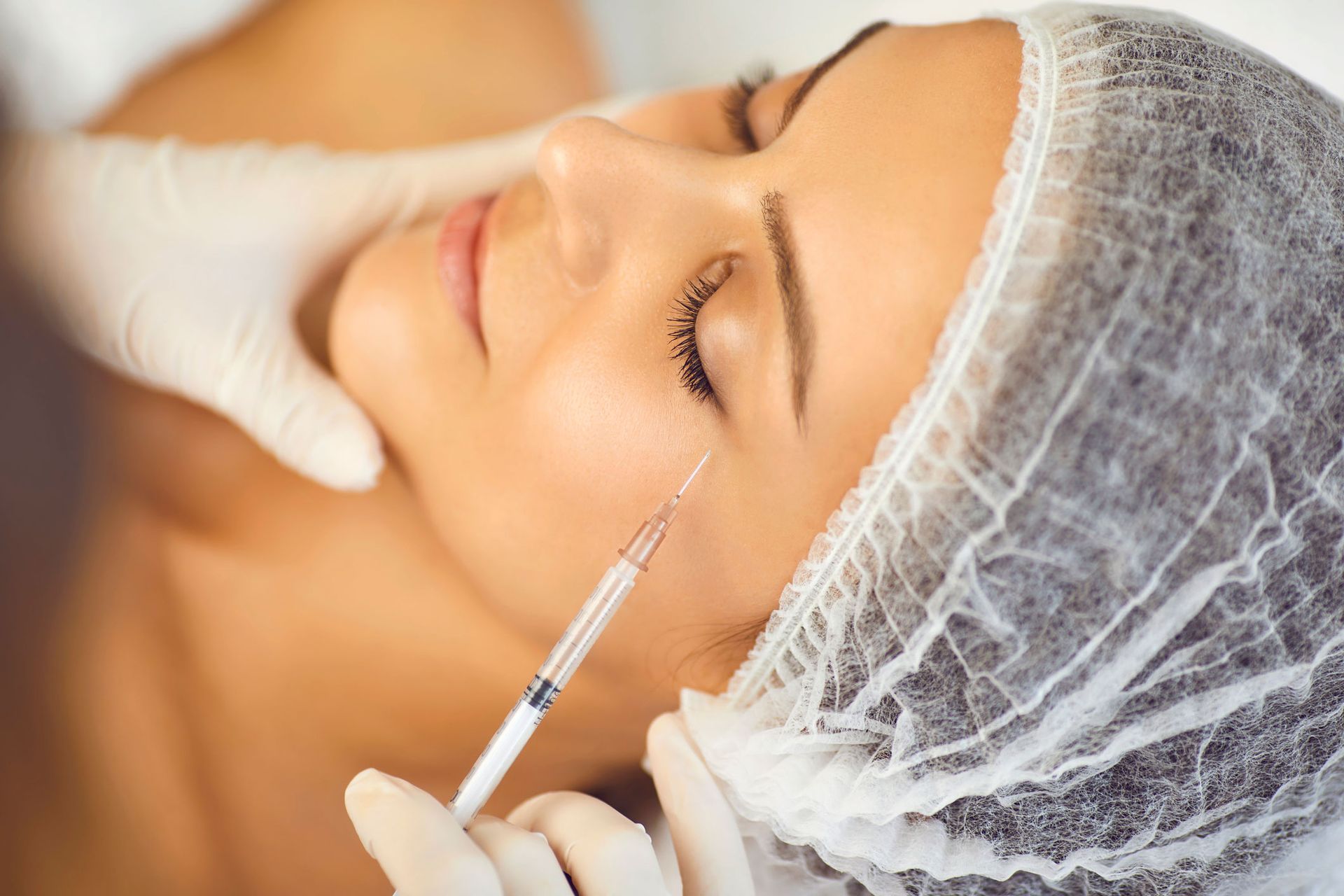 Person receiving a facial injection near the eye, in a medical setting. Person receiving a facial injection near the eye, in a medical setting.