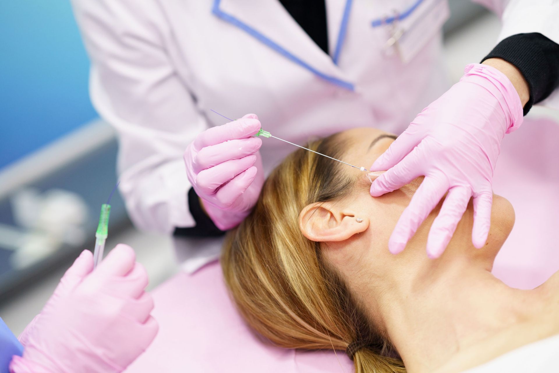 Woman receiving cosmetic procedure with thread, in clinic, medical staff in pink gloves. Woman receiving cosmetic procedure with thread, in clinic, medical staff in pink gloves.