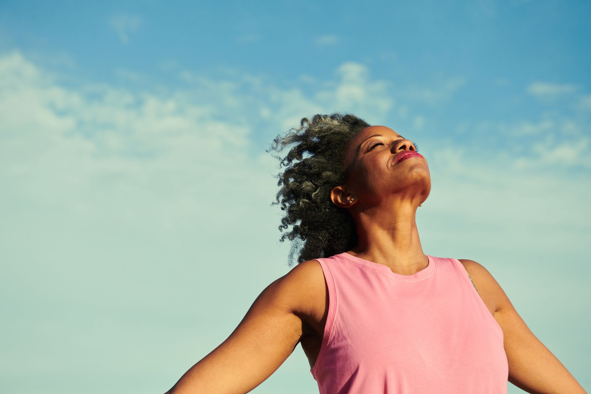 Three women smiling and taking a selfie at a beach, one wearing a scarf.