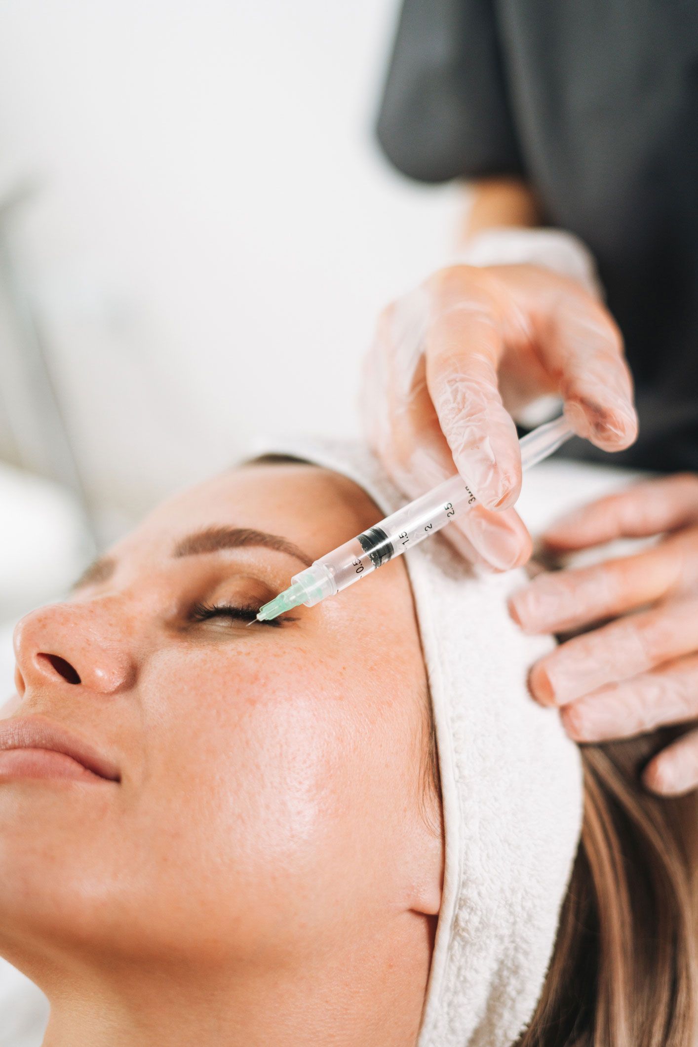 A person receiving an under-eye injection at a medical office. A person receiving an under-eye injection at a medical office.