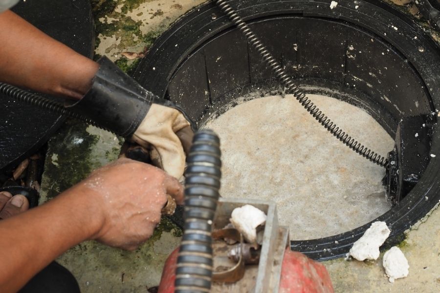 Technician removing wet insulation from behind a water heater in a residential garage, with extraction equipment visible nearby
