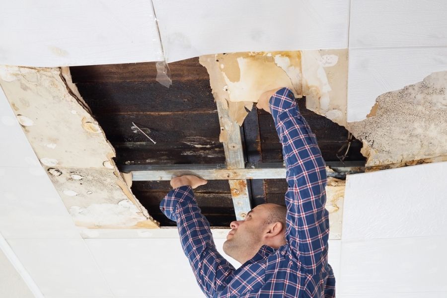 Finished ceiling repair with fresh drywall and texture matching the surrounding area, painter's tape still visible at the edges
