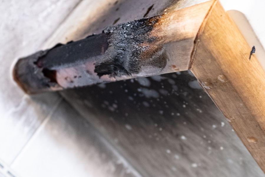 Charred wood beam with heavy soot residue from smoke damage in a Florida home