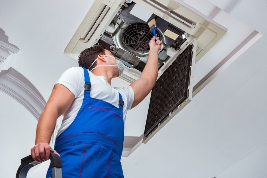 HVAC technician servicing a ceiling-mounted AC unit in a Central Florida home